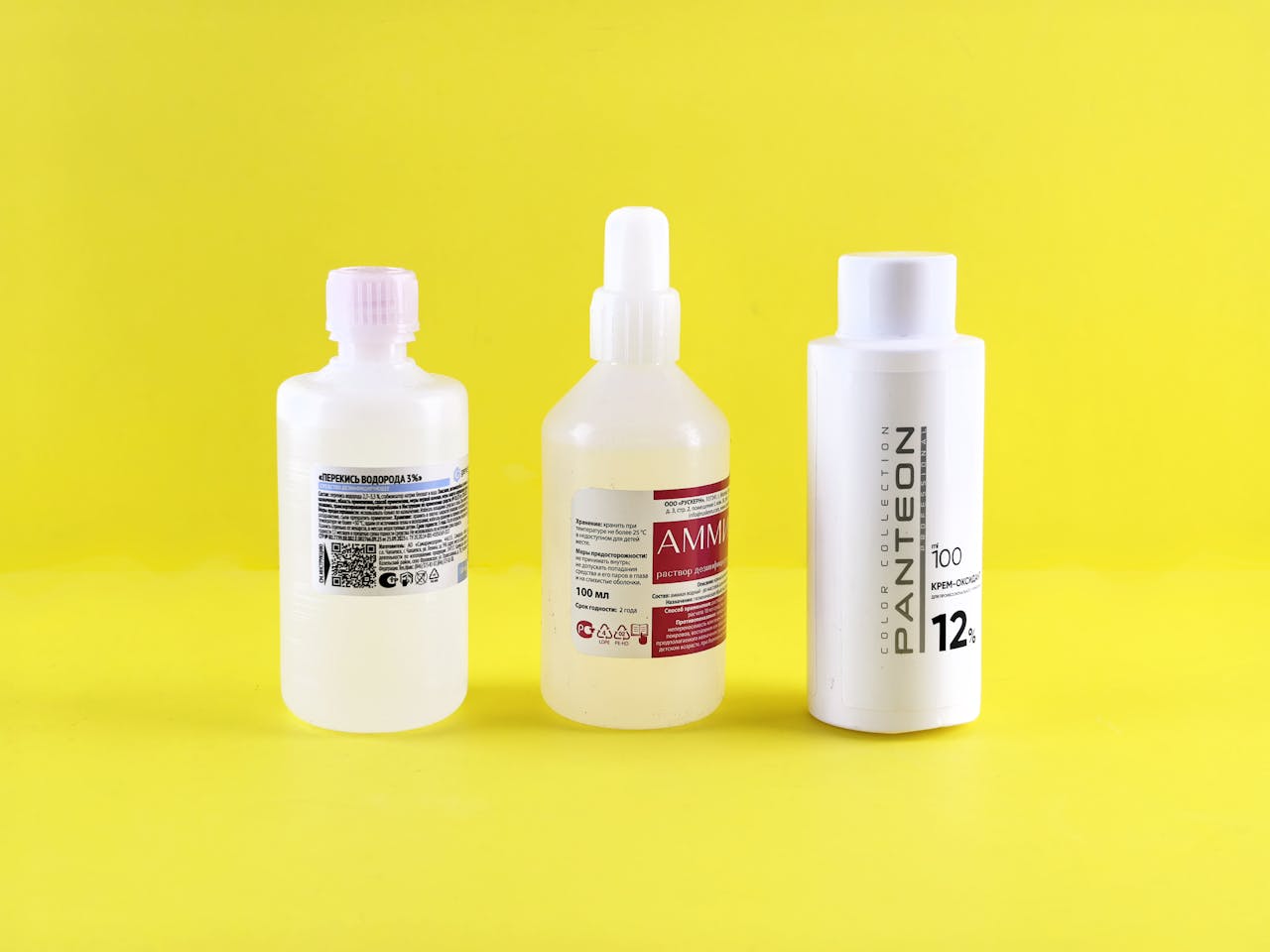Three bottles with labels on a vibrant yellow surface emphasizing chemical substances.