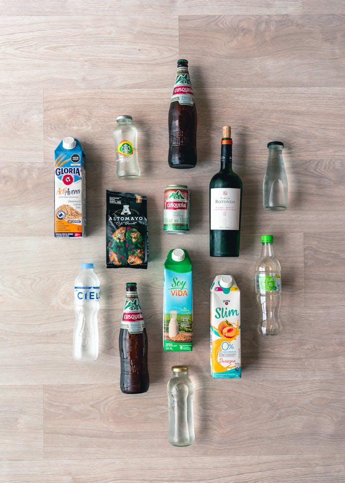 A variety of beverage bottles and cartons arranged on a wooden floor.