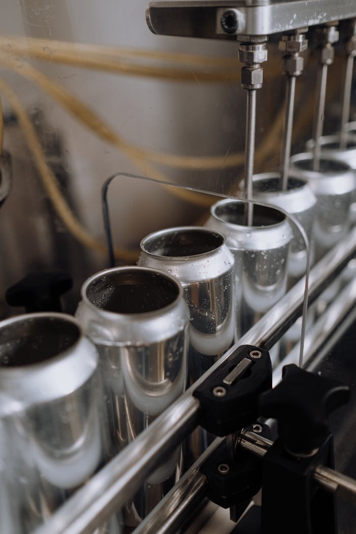 Services-02 Close-up view of an automated can filling line in a brewery showcasing aluminum cans and machinery.