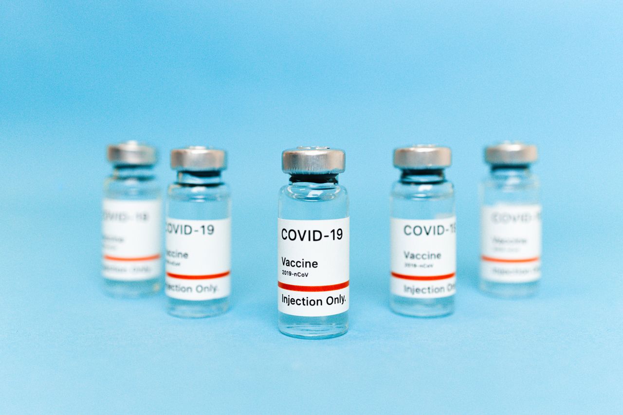 digital A set of COVID-19 vaccine vials, labeled for injection only, on a blue background.