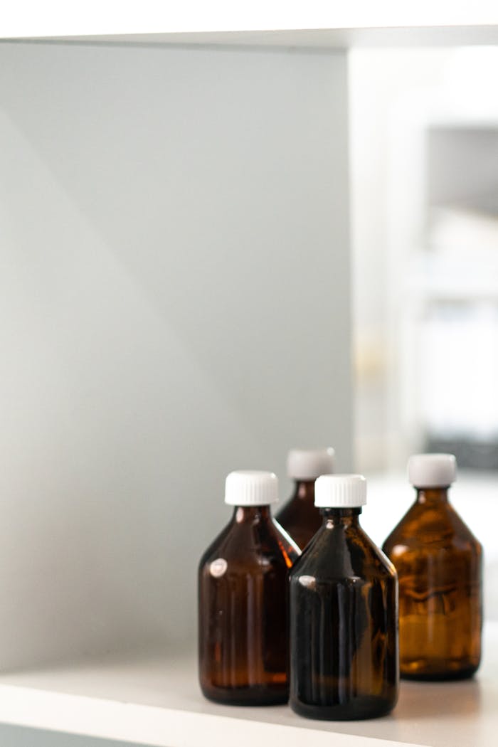 Services-03 Four brown glass bottles with white caps on a shelf, ideal for storage or medical concepts.